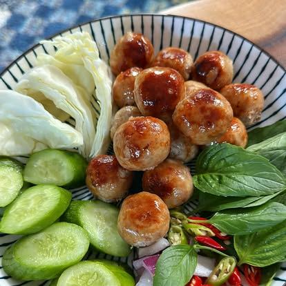 Look Isaan sausages plated with cucumber, chili, and Thai basil